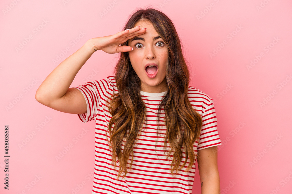 Young caucasian woman isolated on pink background shouts loud, keeps eyes opened and hands tense.