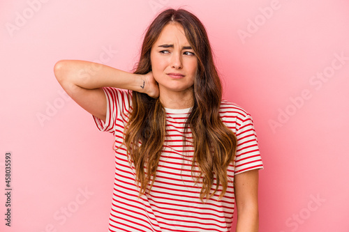 Young caucasian woman isolated on pink background touching back of head, thinking and making a choice.