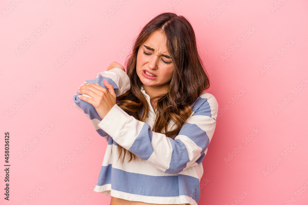 Young caucasian woman isolated on pink background massaging elbow, suffering after a bad movement. Young caucasian woman isolated on pink background massaging elbow, suffering after a bad movement.