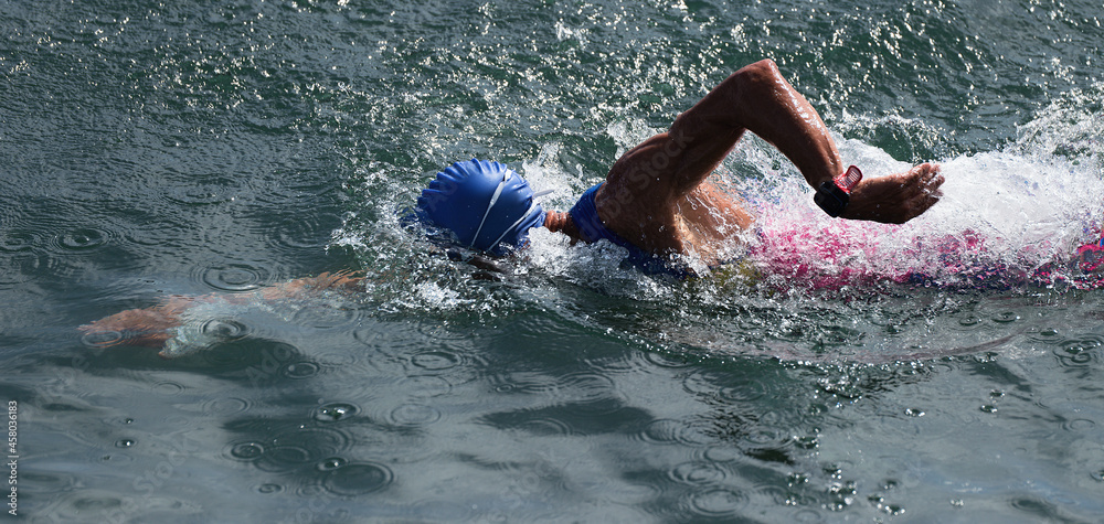 Man swimmer swimming crawl in blue sea, race for triathlon