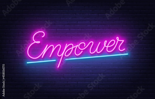 Empower neon lettering on brick wall background.