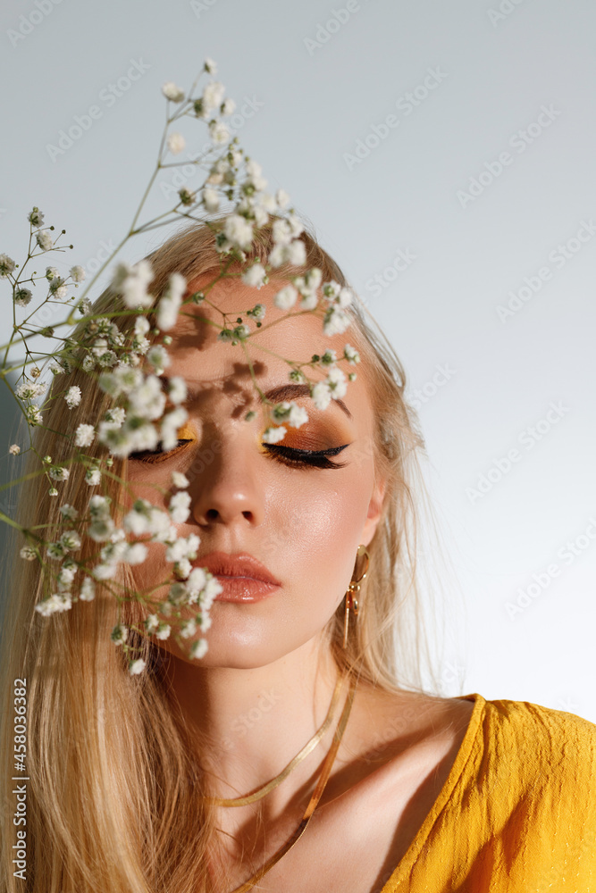 blonde with bright autumn fashion makeup and shade from flowers on her face. close-up.