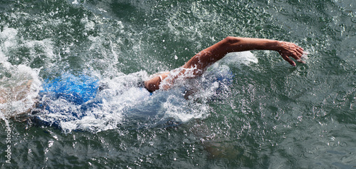 Man swimmer swimming crawl in blue sea, race for triathlon