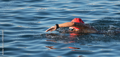 Woman swimmer swimming crawl in blue sea, race for triathlon