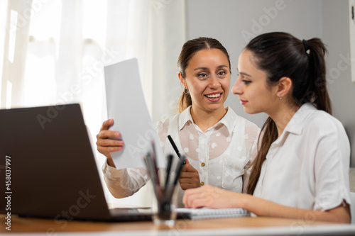 Mujeres de negocio corroboran datos en un papel mientras trabajan en la oficina.