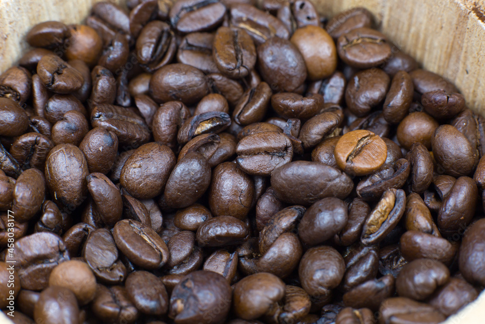 Fototapeta premium Roasted coffee beans in the wooden pot. Close up, macro photo.