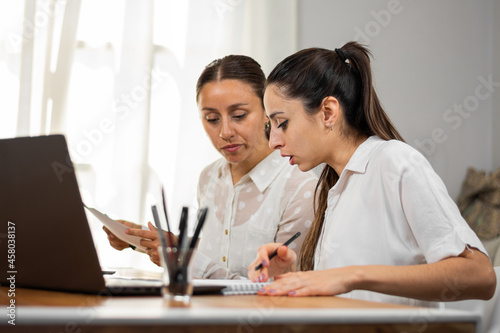 Mujeres de negocio conversan en la oficina mientras trabajan.