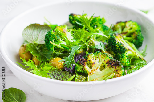 Green salad with grilled broccoli and olives in white bowl. Vegan food, detox, healthy food concept