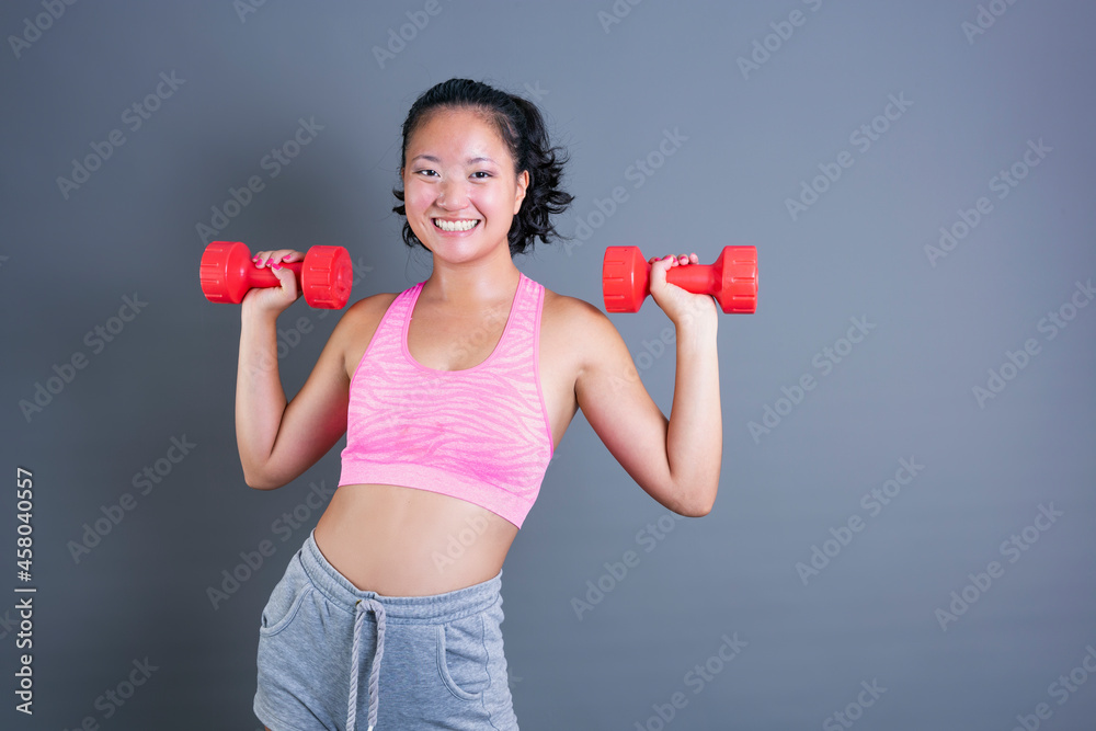 pretty young chinese girl exercising with dumbbells looking straight ahead pretty young chinese girl exercising with dumbbells looking straight ahead
