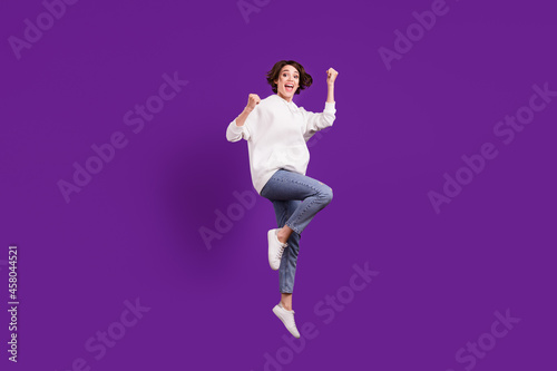 Full size photo of young funky funny crazy girl jumping raise fists in victory triumph isolated on violet color background