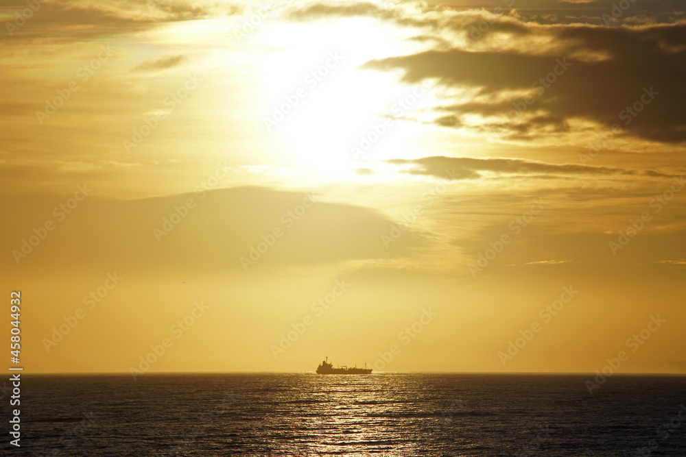 Morning in the open ocean. Sunrise and the silhouette of a ship on the horizon. Atlantic.