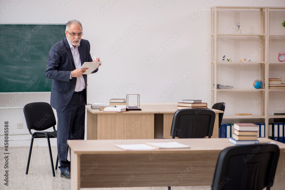Old male teacher in front of blackboard Old male teacher in front of blackboard