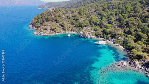 Aerial drone photo of pleasure yacht anchored in crystal clear bay and turquoise beach. uninhabited island in mediterranean sea. Place for swimming in sea while tourist boat trip © Klemenso