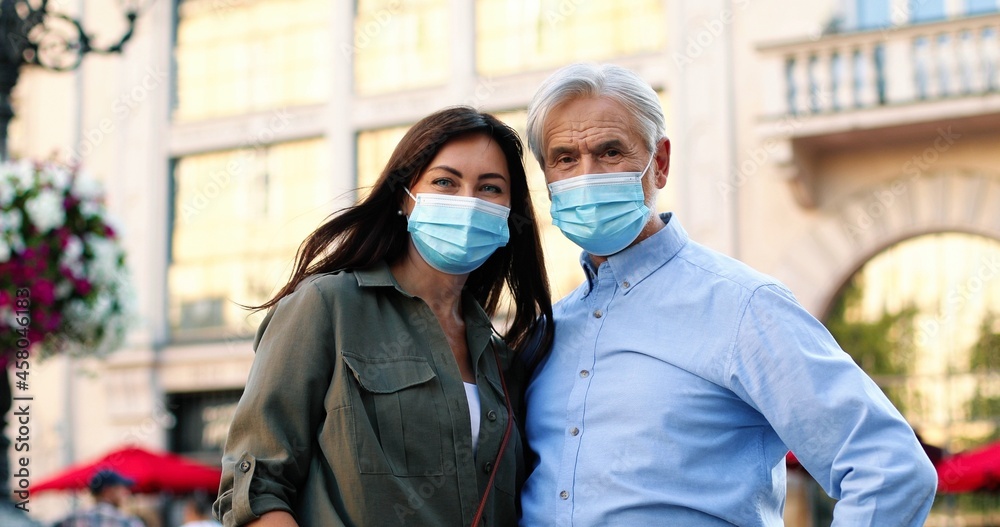 Pandemic period. Waist up portrait view of the senior man and his daughter wearing protective face mask looking at each other with tenderness while walking during quarantine Pandemic period. Waist up portrait view of the senior man and his daughter wearing protective face mask looking at each other with tenderness while walking during quarantine