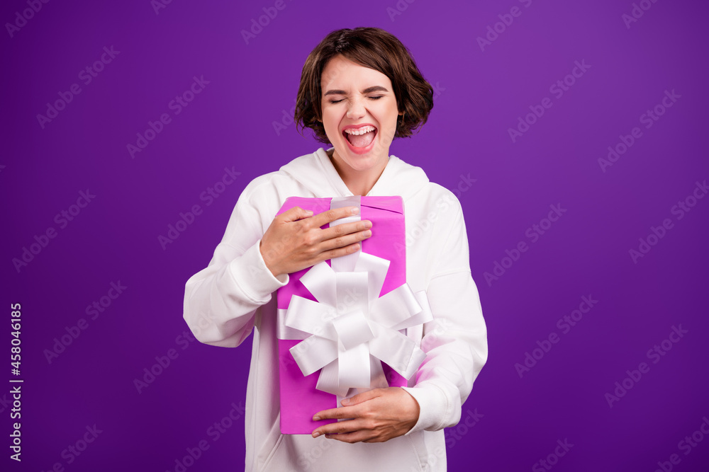 Photo of good mood positive screaming girl hug embrace birthday present excited isolated on purple color background Photo of good mood positive screaming girl hug embrace birthday present excited isolated on purple color background