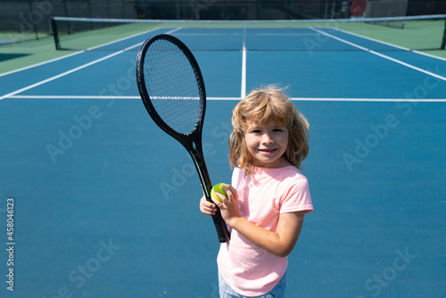Child boy tennis beginner player on outdoor tennis court. © Volodymyr