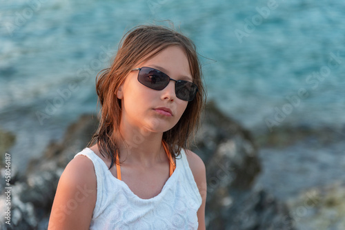 Happy girl with sunglasses standing on the cliff 
