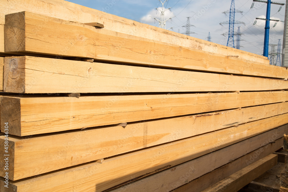 Ταπετσαρία A stack of softwood lumber of yellow color against the blue sky and power lines