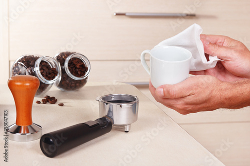 Coffeemaker wipes cup before making espresso above table.