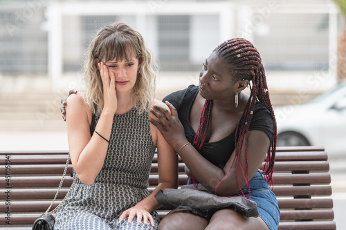 Adult woman with worried expression while her friend consoles her