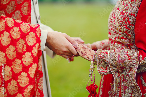 hindu bride walks behind husband holding garb