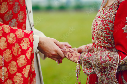 hindu bride walks behind husband holding garb