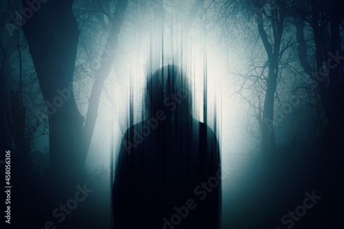 A double exposure of a Silhouette of a mysterious hooded figure without a face. Standing in a forest at night. With a glitch edit