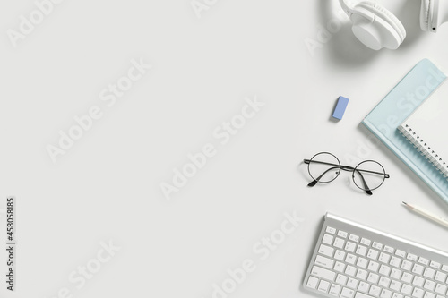 Online learning education, freelance and office work minimalistic flat lay with copy space. Stationery, headphones, notebook, pencil, glasses on white background.
