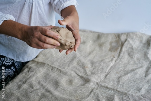 closeup female hands kneading a piece of clay on the table