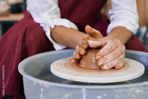 closeup female hands twist clay on a potter's wheel