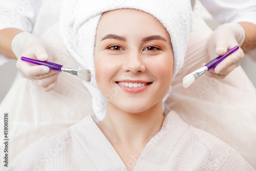 Happy woman with smile use facial treatment mask on skin face in spa beauty salon