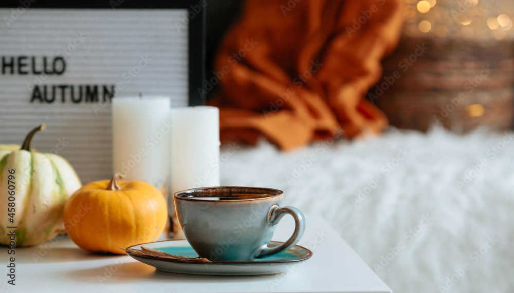 Still-life. A blanket, pumpkins and a cup of tea on the coffee table in the home interior of the living room. A cozy autumn concept.
