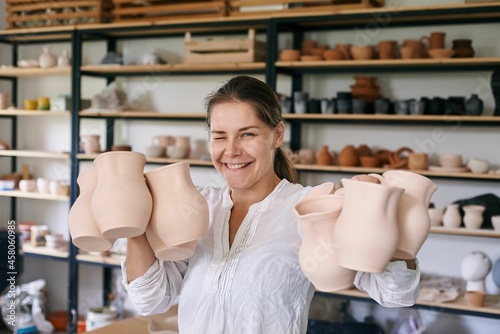 woman artisan ceramist holds handmade clay jugs in her hands