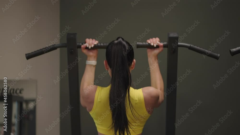 Hispanic Woman Does Pull-Ups On Gravitron For Strengthening The Shoulder Muscles In The Gym. A woman does the exercises correctly, pulling up with a straight back. pull-ups on the simulator Hispanic Woman Does Pull-Ups On Gravitron For Strengthening The Shoulder Muscles In The Gym. A woman does the exercises correctly, pulling up with a straight back. pull-ups on the simulator