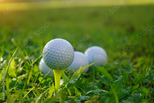 Golf ball on tee in beautiful golf course at sunset background.