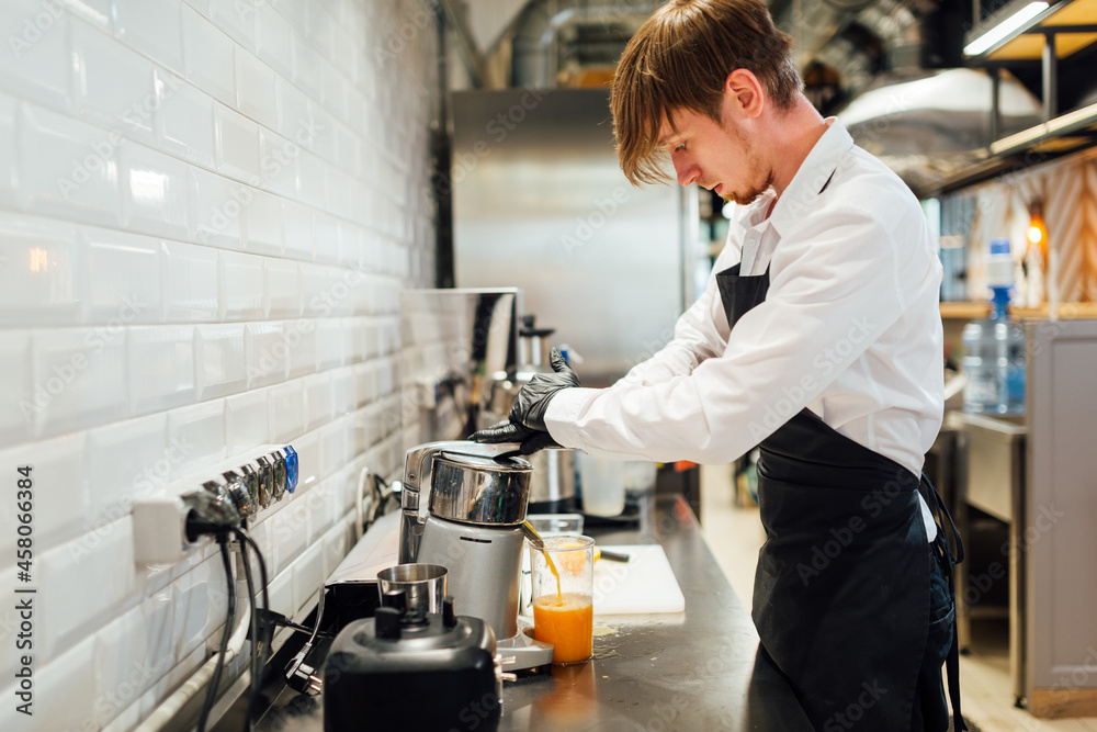 A cafe worker makes orange juice in a juicer. Catering kitchen work. A cafe worker makes orange juice in a juicer. Catering kitchen work.