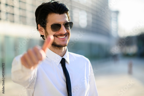 Young businessman outdoor wearing sunglasses and giving thumbs up