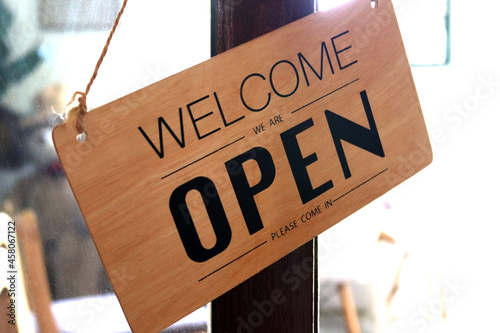 "Open" on cafe or restaurant with incline sign hang on door at entrance.