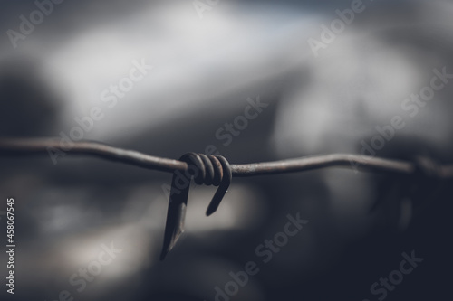 Barbed wire fence against dramatic, dark sky