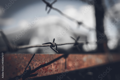 Fotografía Barbed wire fence against dramatic, dark sky