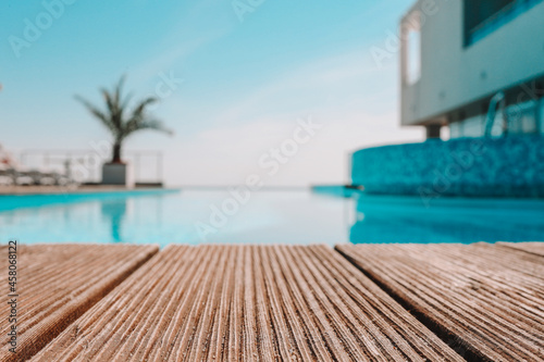 Fotografia Empty wooden deck with swimming pool , Beautiful minimalist pool side view with clear blue sky