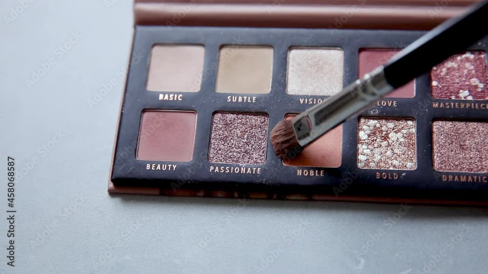 Brush gains up nude glitter eye shadow for makeup, macro close up. Tools for make up and cosmetics palette. Details of morning routine make-up process. Decorative cosmetics Brush gains up nude glitter eye shadow for makeup, macro close up. Tools for make up and cosmetics palette. Details of morning routine make-up process. Decorative cosmetics
