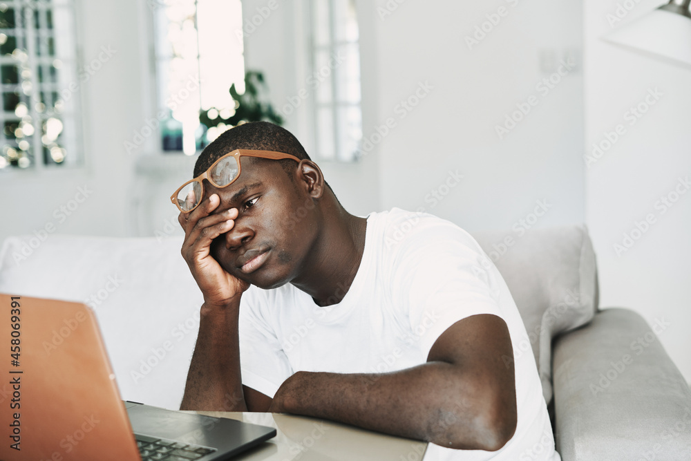 Fototapeta premium man african appearance at home in front of laptop working online