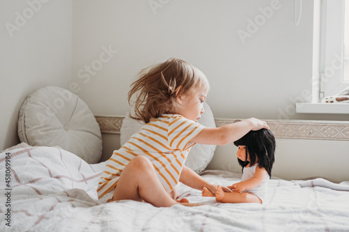 Toddler girl playing with her doll at home