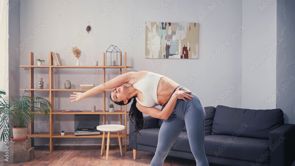 Obraz premium Slim sportswoman bending during home work out