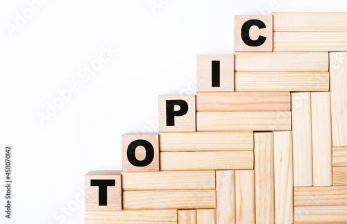 On a light background, wooden blocks and cubes with the text TOPIC