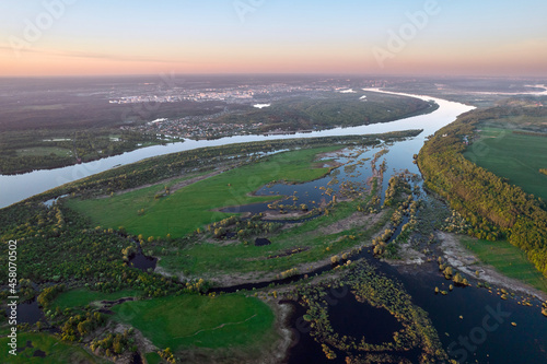 Aerial view above the river and field of grass