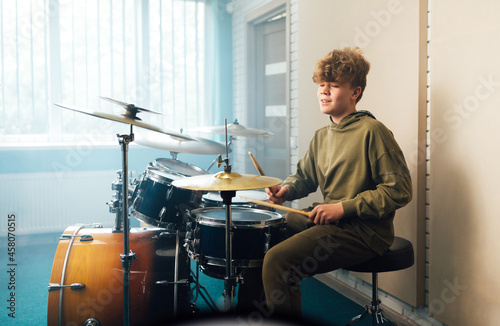 Photographie A boy enjoys music playing the drum set
