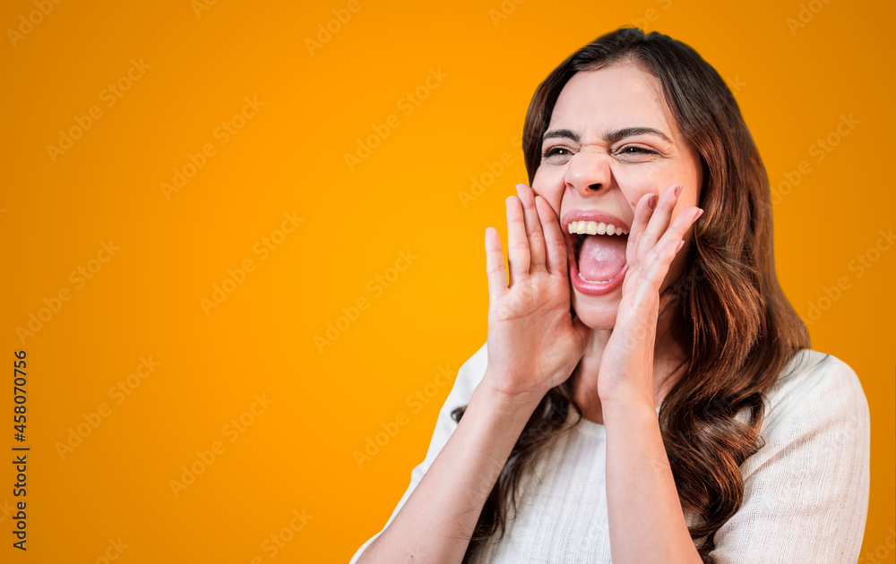 Beautiful Latin woman screaming loud to side with hand on mouth. Communication concept.