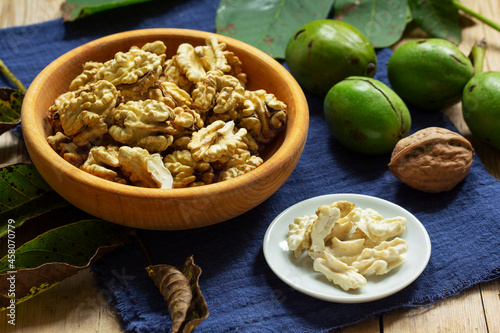 Young walnuts, shelled and in shell, walnut leaves. Rustic style.